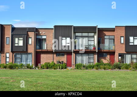 Moderne Stadthäuser mit gemischten Fassadenverkleidung und grünen Rasen vor Ihnen. Stockfoto