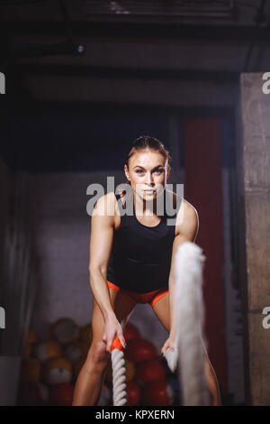 Passen Sportlerin und trainieren Sie im Fitnessraum, Querschnitts Übung mit Seilen Stockfoto