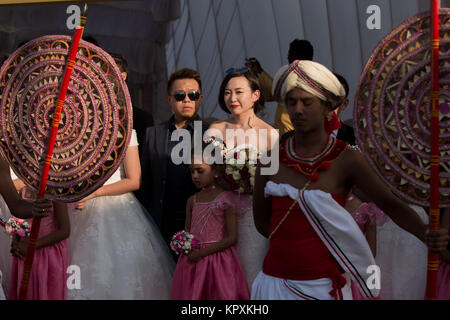 Colombo, Sri Lanka. 17. Dezember, 2017. Ein chinesisches Paar posiert für ein Foto mit einer Sri Lankan Flower Girl während einer Messe Hochzeit in Colombo, Sri Lanka. Credit: vimukthi Embuldeniya/Alamy leben Nachrichten Stockfoto