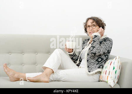 Reife Frau mit Telefon, Tee trinken. Stockfoto