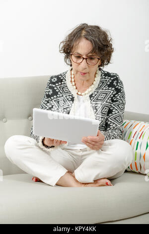 Schöne, reife Frau mit einem Tablett auf dem Sofa Stockfoto