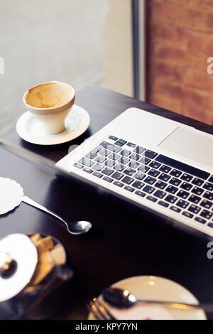 Laptop und eine Tasse Kaffee mit Zucker Schale Stockfoto