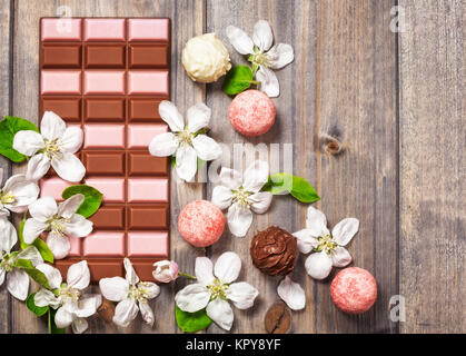 Erdbeere Schokolade Bar, Pralinen und Blumen Apfel auf hölzernen Hintergrund. Köstliches Dessert. Ansicht von oben flach legen Stockfoto