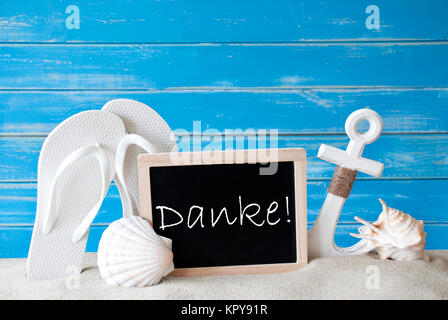 Schiefertafel mit deutschen Text Danke, Danke. Blau Holz- Hintergrund. Sommer Karte mit Urlaubsgrüße. Strand Ferienhäuser symbolisiert durch Sand, Flip Flops, Anker und Shell. Stockfoto