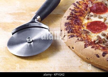 Pizza-Hobel und Pepperoni Pizza Stockfoto