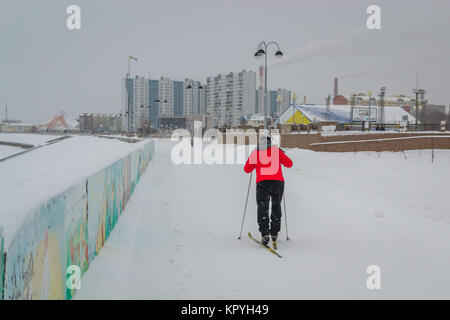 Junger Mann Skifahren in eine rote Jacke entlang des Flusses Stockfoto