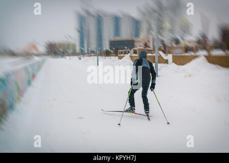 Junger Mann Skifahren in einer schwarzen Jacke entlang des Flusses Stockfoto