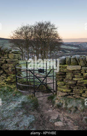 Kissing Gate mit 20 Bäume am Hang oberhalb des Dorfes Hayfield, Derbyshire an einem frostigen Wintermorgen. Stockfoto