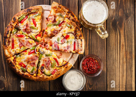 Hausgemachte Pizza mit Speck, Paprika und Mais auf einem Holzbrett serviert. Ansicht von oben Stockfoto