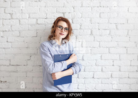 Glückliche junge Geschäftsfrau mit einem Ordner im Bürogebäude Stockfoto