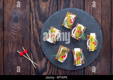 Kanapees mit Roggenbrot, Hering und Pickles auf einem festlich gedeckten Tisch. Valentinstag Konzept oder Hochzeit. Stockfoto