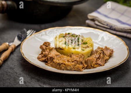 Confit Schweinekamm mit Kartoffelpüree auf steinernen Tisch Stockfoto