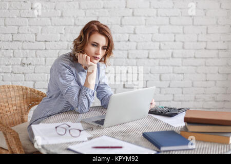 Gelangweilte junge Frau im Büro mit einem Laptop arbeiten und starrte auf Bildschirm Stockfoto