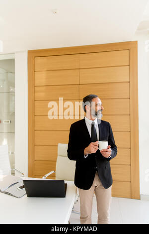 Blick auf mittlerem Alter Geschäftsmann mit Kaffeepause in modernen Büro Stockfoto