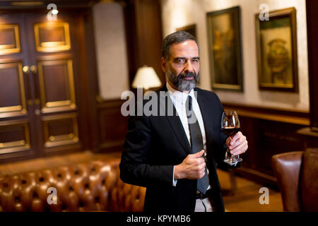 Schöne elegante Geschäftsmann trinken Rotwein in bar Stockfoto