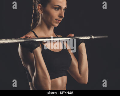 Schöne junge Frau in einer Jogginghose, Anheben einer Langhantel Stockfoto