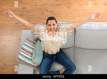 Blick von oben auf eine schöne und glückliche junge Frau auf der Couch Stockfoto