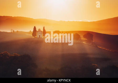 Toskana Landschaft bei Sonnenaufgang mit einer kleinen Kapelle von Madonna di Vitaleta, San Quirico d'Orcia, Italien. Stockfoto