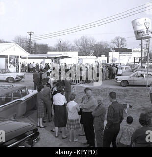 1960er Jahre, nun, das ist eine lange Schlange... historisches Bild aus dieser Zeit zeigen amerikanische Männer und Frauen außerhalb ein Kentucky Fried Chicken fast food in der Hoffnung auf einen der Geldpreise im Store, USA Queuing. Stockfoto
