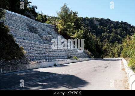 Eine Reihe von trat zurück Gabionen, Stein gefüllt Käfige, Linie a Mountain Road Schutz der Damm von Erosion und zum Schutz der Straße. Stockfoto