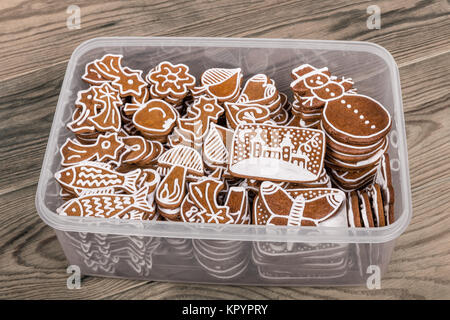 Schönen traditionellen handgemachten Weihnachten Lebkuchen. Transparente Kunststoffbox mit Haufen von Hand - Gebäck auf einem Holz Hintergrund eingerichtet. Stockfoto