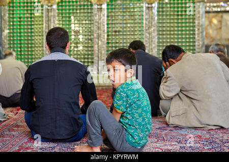 Yazd, Iran - 21. April 2017: Schrein des Prinzen Fazel, den Jungen im Grundschulalter ist im Gebet Hall, wenn erwachsene Männer beten langweilig. Stockfoto