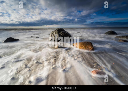 Ostsee in der hellen Hintergrundbeleuchtung und rauer See mit Steinen im Wasser Stockfoto