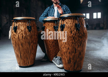 Männliche Schlagzeuger spielt auf hölzernen Fässern im Factory Shop, Musiker in Bewegung. Bongo, musikalische Schlaginstrument, ethnische Musik Stockfoto