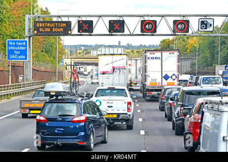 M25 Verkehrsstaus-Schilder auf der Autobahn weisen auf ein Hindernis vor zwei Fahrspuren hin. Schlangen sind geschlossen, da die Fahrzeuge am Freitag Nachmittag zur Hauptverkehrszeit in North London UK auf zwei Fahrspuren zusammenlaufen Stockfoto