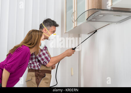 Männliche Arbeiter Sprühen von Insektiziden Unterschrank Stockfoto