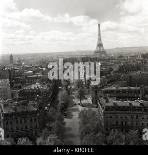 1950, Paris, Frankreich, und eine historische Ansicht von Overhead durch eine lange Allee mit der berühmten Schmiedeeisen Tower, den Eiffelturm in der Ferne. Man kann sehen, in dieser Zeit so groß und die Festlegung der Turm wurde im Vergleich zu den anderen Gebäuden in der Stadt, die eine einheitliche Höhe waren. Stockfoto