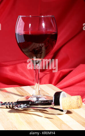 Weinkorken, Korkenzieher und Glas mit Rotwein Trauben auf Holztisch. Stockfoto