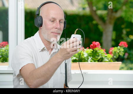 Reifer mann Hören von Musik mit seinem Telefon Stockfoto