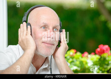 Reifer mann Hören von Musik Stockfoto