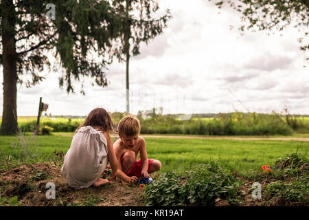 Jungen und Mädchen spielen mit Spielzeug Autos im Garten Stockfoto