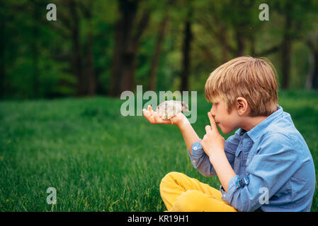 Junge sitzt im Garten hält ein Baby chick Stockfoto