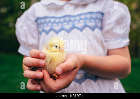 Stehendes Mädchen in einem Garten Holding ein Küken Stockfoto