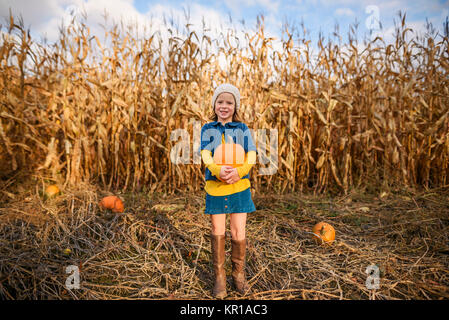 Stehendes Mädchen in einer Holding ein Kürbis Pumpkin Patch. Stockfoto
