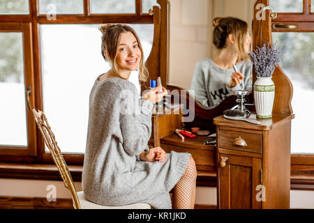 Frau sitzt am Schminktisch im Winter Stockfoto