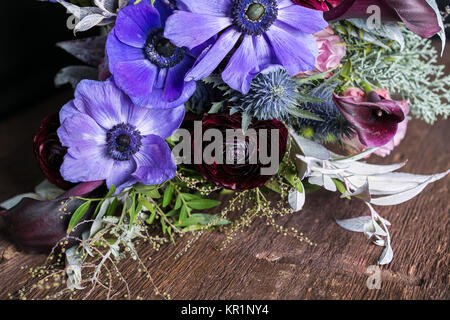 Florale Muster, Hochzeit, Feder Konzept. Auf hölzernen Tisch Es ist bunter Blumenstrauß, inmitten von wunderschönen Blumen wie Blau und Lila anemons, rosa Lilien und geschwollene battercups gibt es auch Disteln Stockfoto