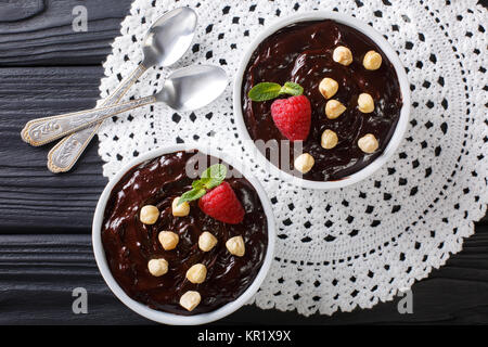 Süße Schokolade Pudding mit Haselnüssen, Minze und Himbeeren in der Nähe eingerichtet - auf den Tisch. horizontal oben Ansicht von oben Stockfoto