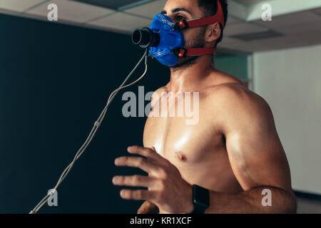 Sport Mann laufen auf Laufband und seine Fitness Performance Monitoring. Männliche Läufer tragen Maske auf Laufband in Sport Science Laboratory. Stockfoto