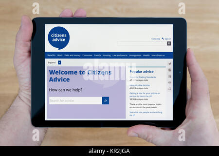 Ein Mann schaut auf die Bürger Beratung Website auf seinem iPad tablet device, Schuß gegen einen hölzernen Tisch top Hintergrund (nur redaktionelle Nutzung) Stockfoto