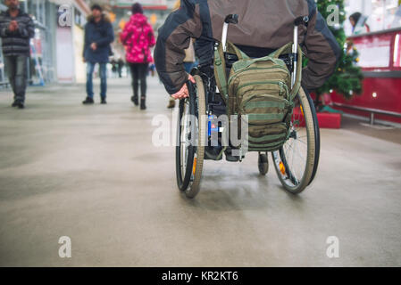 Kein Gesicht im Alter behinderte, behinderte Person auf Rädern Stuhl unter den Menschen ohne Behinderungen in die Mall von Markt. Selektive konzentrieren. Platz für Text Stockfoto
