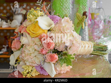 Foto von einem brautstrauß mit gelben Rosen, calla Lilien, Lavendel Astern, coral Rosen, Hortensien, pfirsich gelb lieferbar und Caspia in Satin gewickelt. Stockfoto