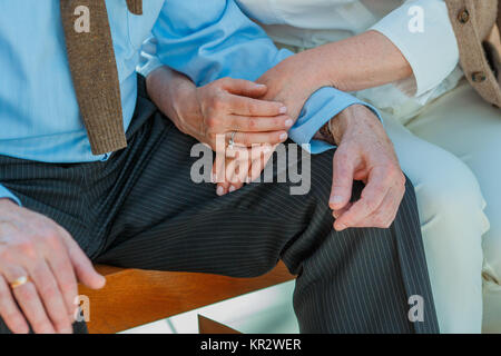 7/8 Schuß des älteren Paares halten sich an den Händen, während sitzen zusammen Stockfoto