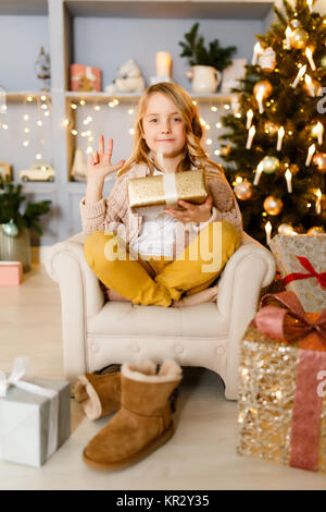 Bild von Mädchen sitzen im Stuhl auf dem Hintergrund von Christbaumschmuck Stockfoto