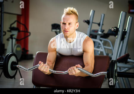 Hübscher junger Mann Training Bizeps im Fitness-Studio Stockfoto