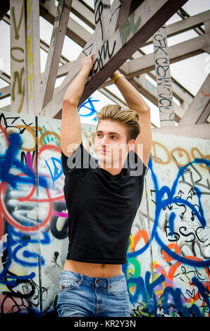 Hübscher blonder junger Mann hängen vom konkreten Struktur Stockfoto