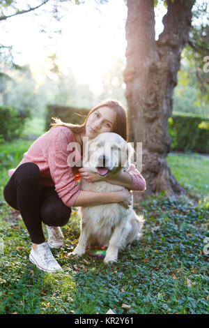 Foto von Mädchen umarmt Hund auf Rasen Stockfoto